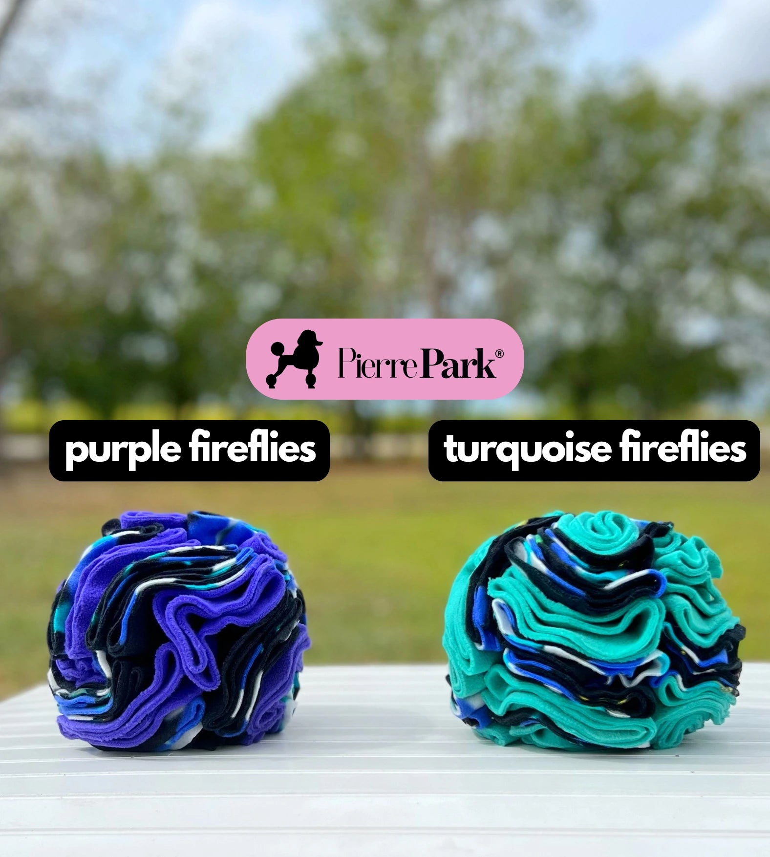 Snuffle ball for dogs by PierrePark, 'purple fireflies' and 'turquoise fireflies', shown outdoors on a table with a tree-lined background. These toys, in deep blue and purple hues, encourage mental stimulation and sensory play for dogs.