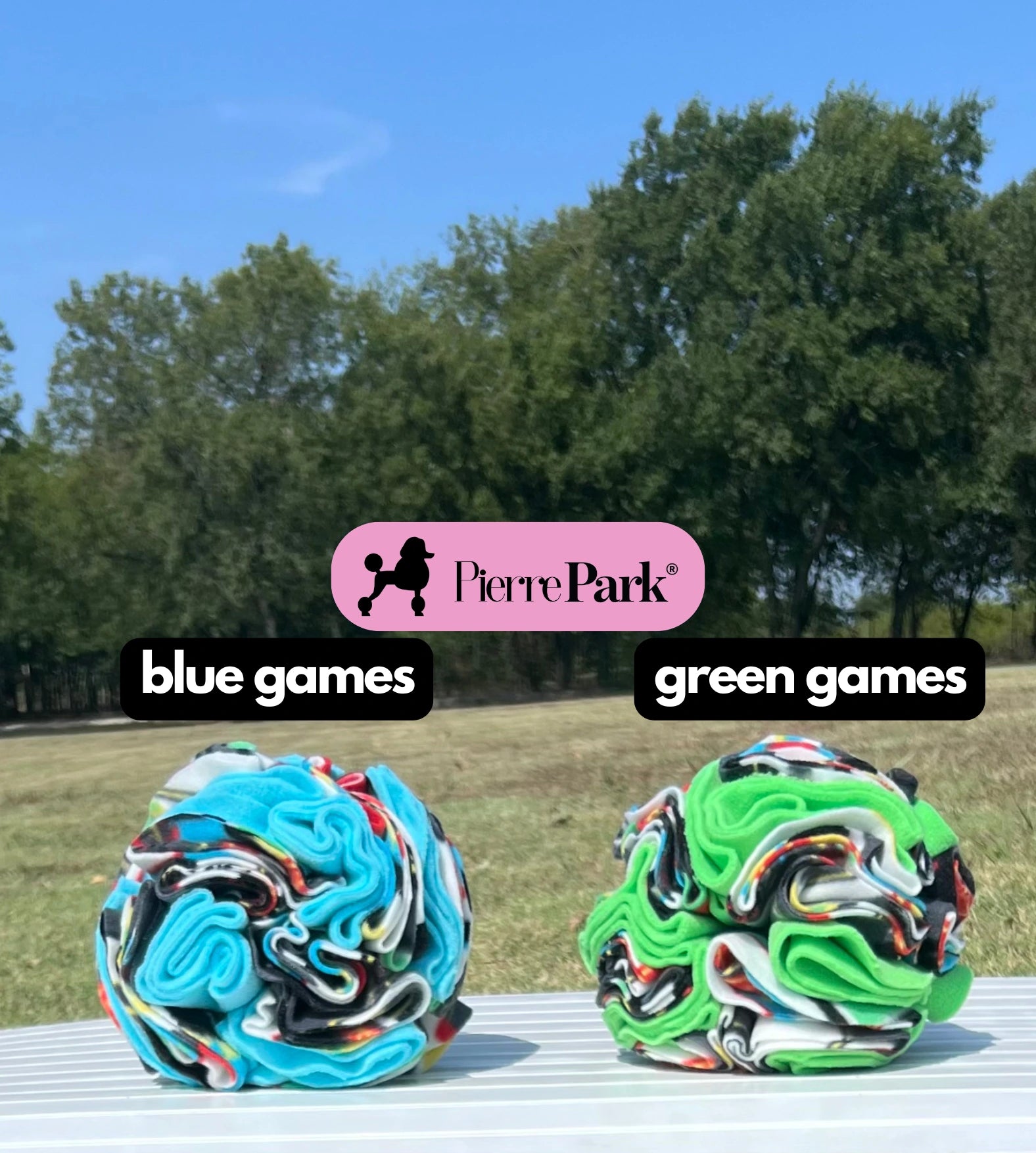 Snuffle ball for dogs by PierrePark, 'blue games' and 'green games', displayed outdoors on a table with a backdrop of lush green trees. These toys feature vibrant color swirls and are designed to engage dogs in enriching sniffing and foraging activities.