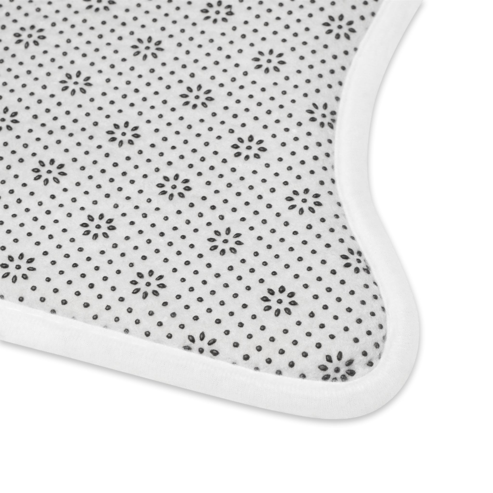 The PierrePark Dog Food Mat in light grey features a close-up of its elegant design: white fabric dotted with black polka dots and small florals, finished with a plain white border. Its absorbent material has a slight curve at one corner, offering both style and functionality.