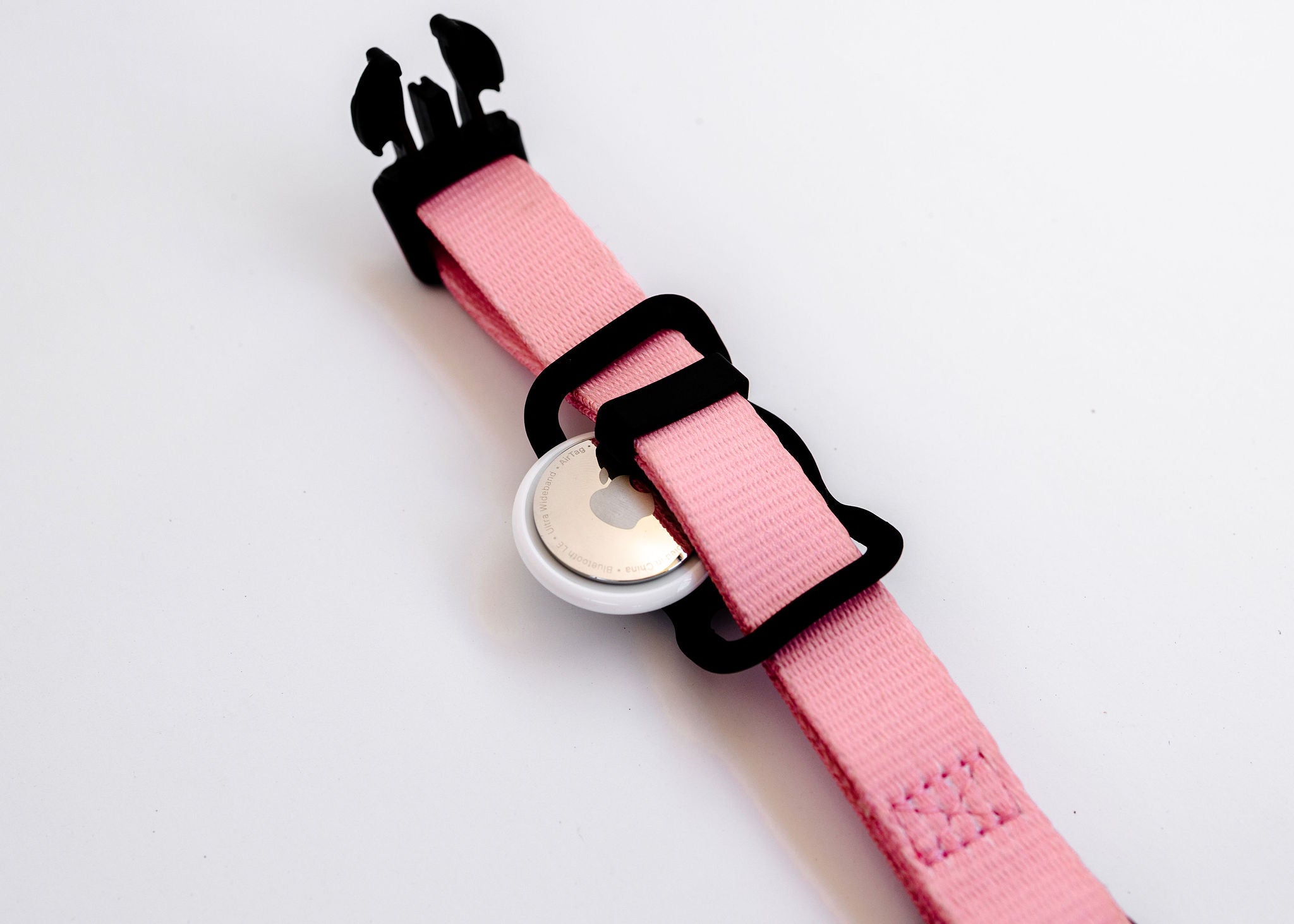 The Pink Dog Collar by PierrePark featuring black buckles and a round location tag is displayed on a white surface.