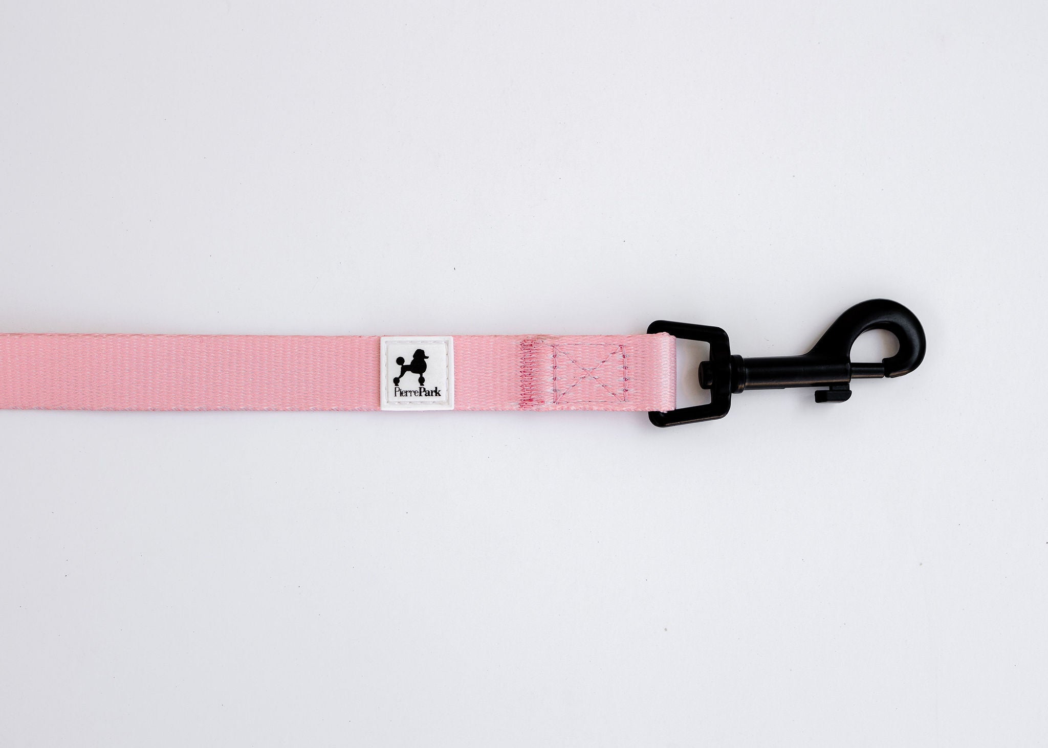 The Pink Dog Leash by PierrePark is displayed on a white background, featuring a pink design with a black metal clip on one end and a label with a dog silhouette.