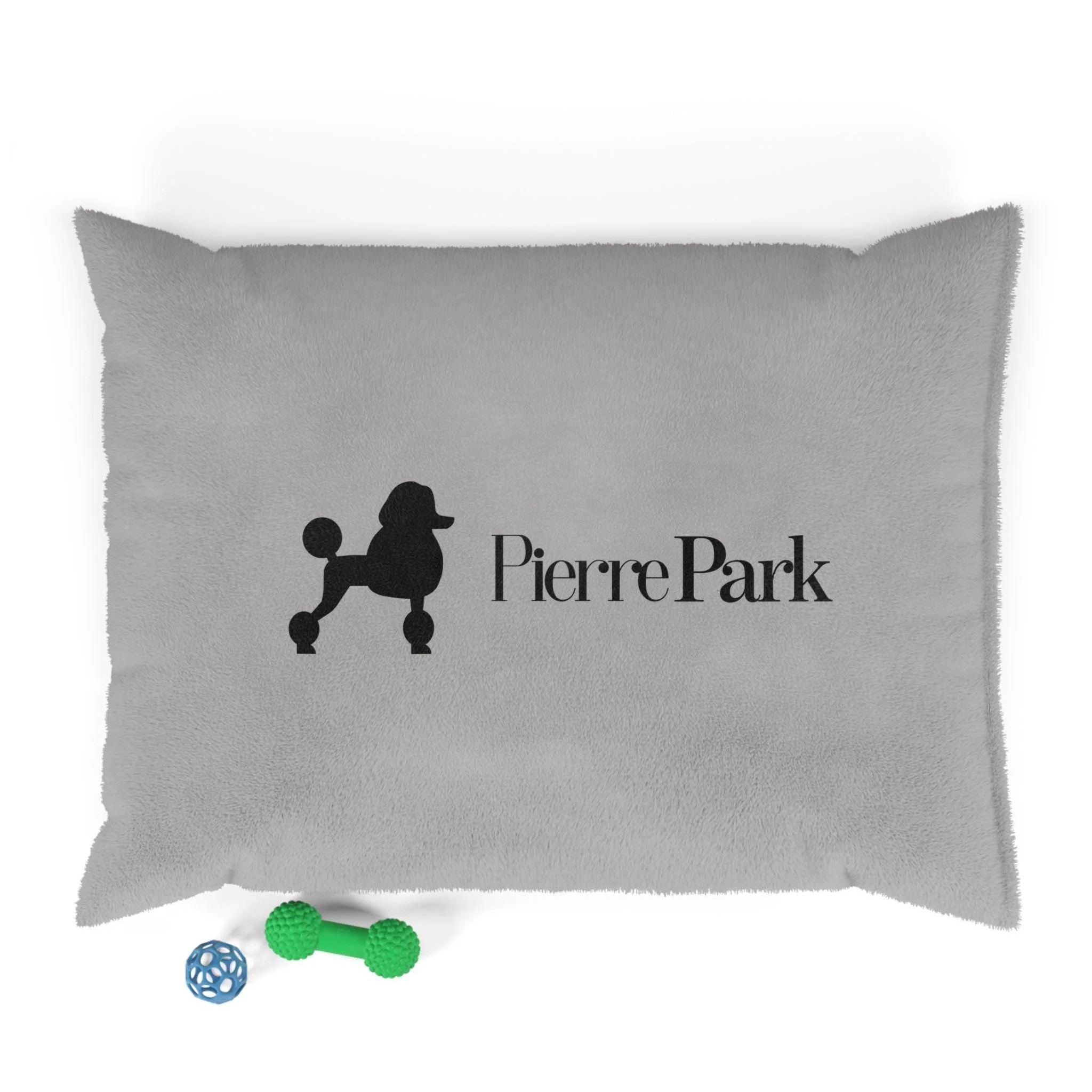 The Perfect Prince Dog Bed by PierrePark features a gray pillow with a poodle silhouette and Pierre Park in black, plus two toys: a green bone and a perforated blue ball for entertainment.