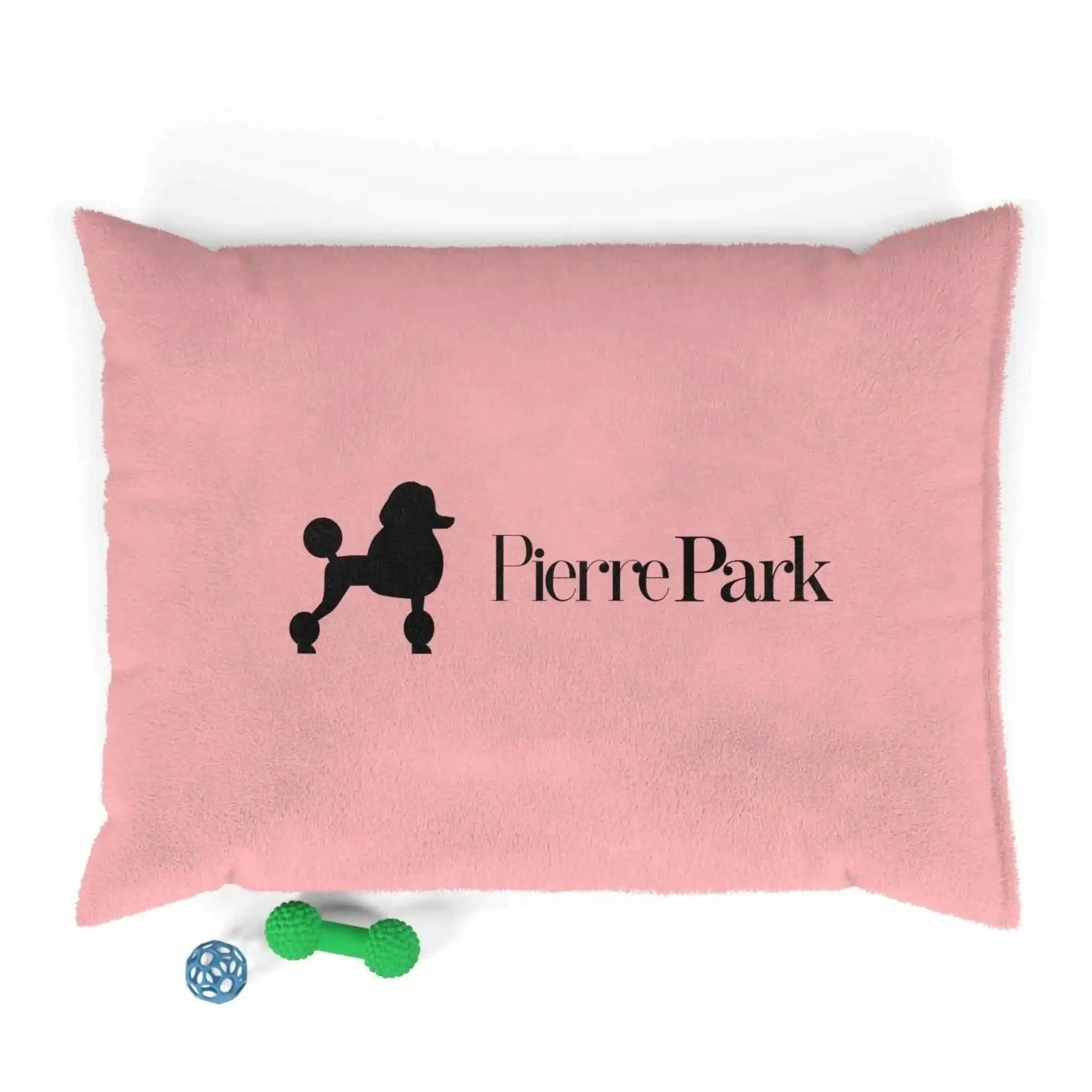 A pink dog bed with the PierrePark logo, accompanied by two small dog toys, showcasing a cozy and inviting space for pets to relax and play.