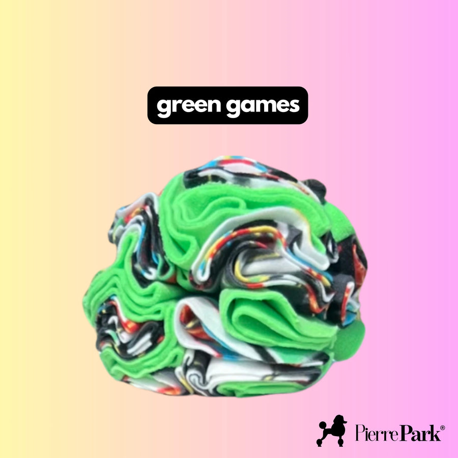 Snuffle ball for dogs by PierrePark labeled 'green games,' displaying vivid green and black swirls on a gentle pastel pink and yellow background. This stimulating dog toy encourages natural foraging behaviors, providing mental and physical exercise.