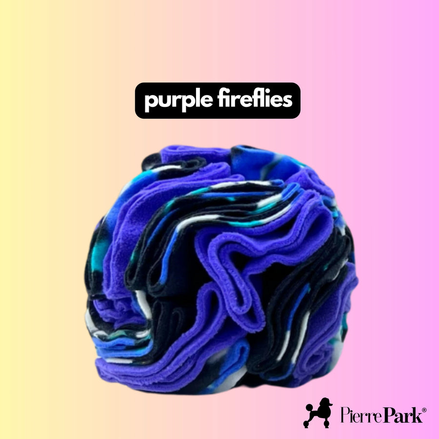 Snuffle ball toy by PierrePark named 'purple fireflies,' showcasing deep shades of purple and blue against a soft pastel pink and yellow gradient background. This engaging dog toy is designed for mental stimulation and sensory play, helping dogs to indulge their natural sniffing and foraging behaviors.